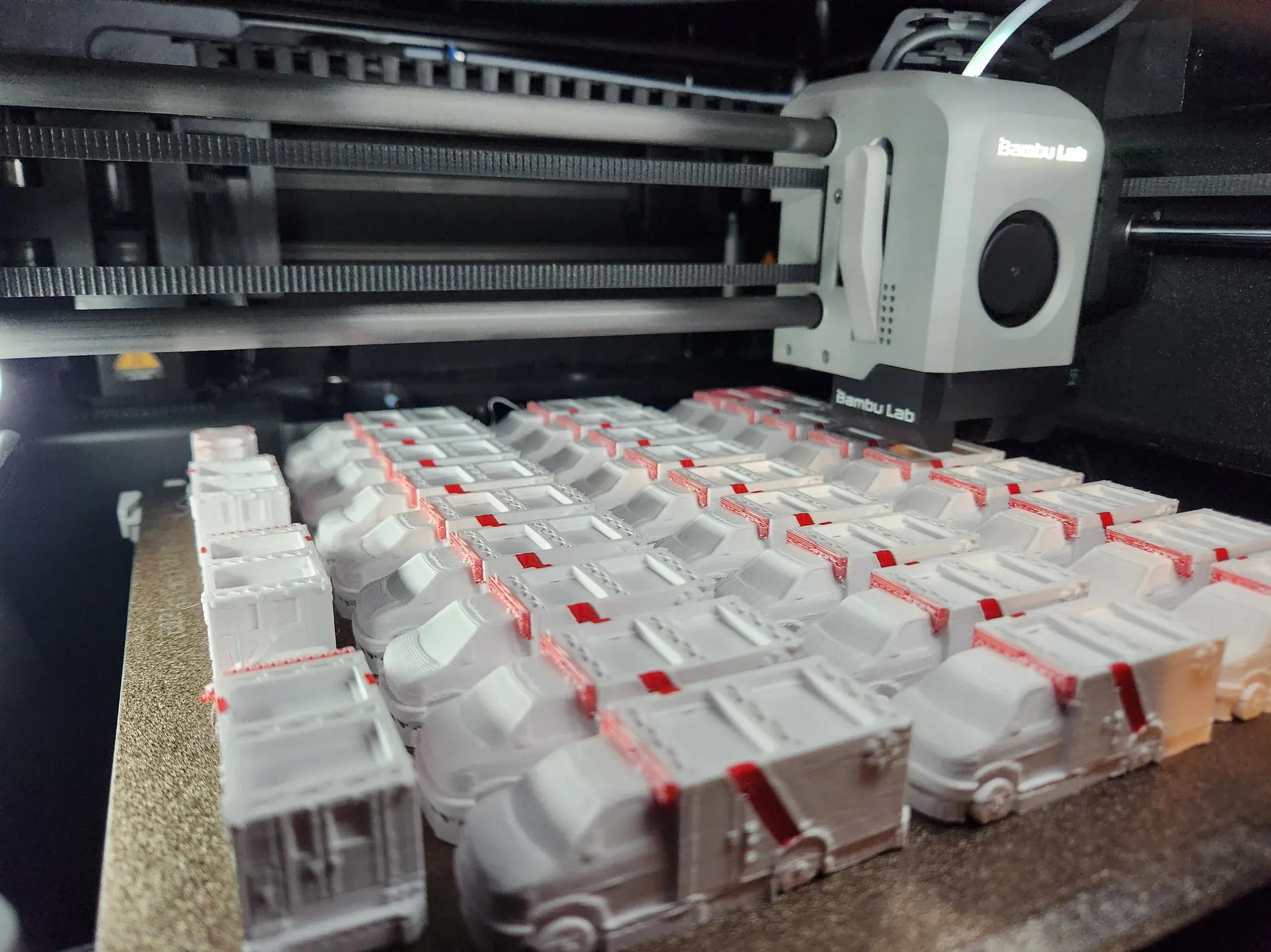 A batch of 3D printed ambulance models on an FDM printer bed
